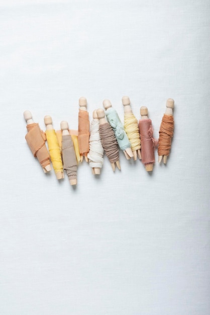 Kolorowe nici i igły na lnianej tkaninie